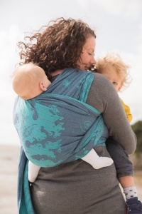 Carnforth Lancashire - Picture of a mother with her back to the camera holding her toddler in arms with one of her twin babies on her back in a baby wrap