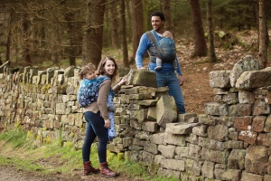 Entwistle Reservoir - Portrait of a mum and dad carrying their two children in Baie Sling wrap while leaning on a wall